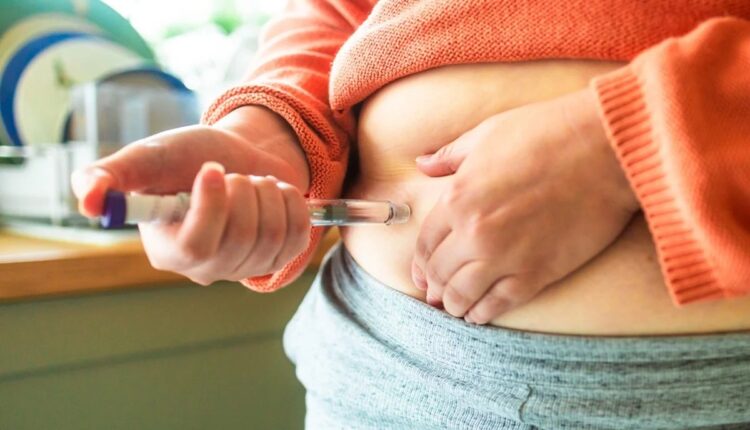 Pessoa aplicando medicamento injetável na barriga