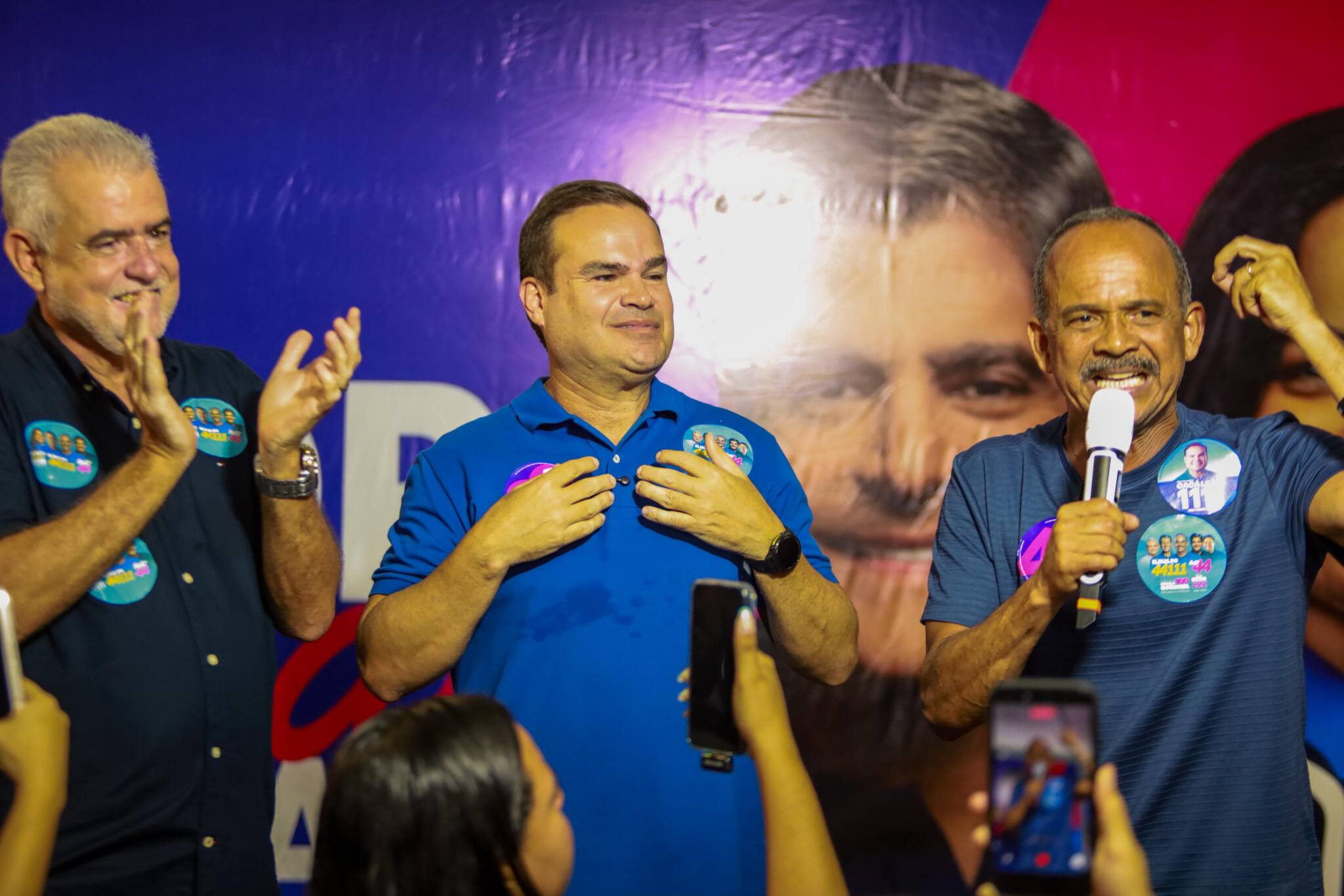 Coca Branco fala ao microfone ao lado de João Leão e Cacá Leão no encontro em Itinga