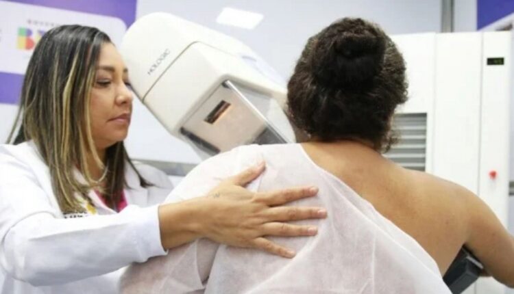 Técnica acompanha paciente durante exame de mamografia