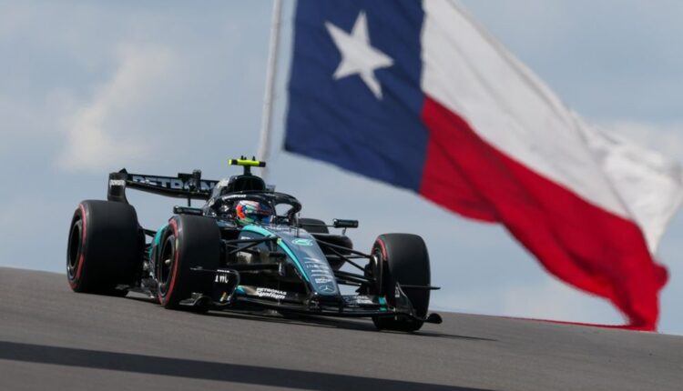 Carro da Mercedes na pista de Austin, com a bandeira do Texas ao fundo