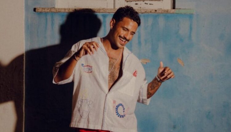 Lucas Pizane dança diante de parede azul