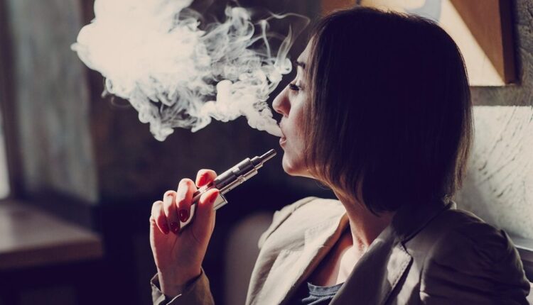 Mulher solta fumaça de cigarro eletrônico