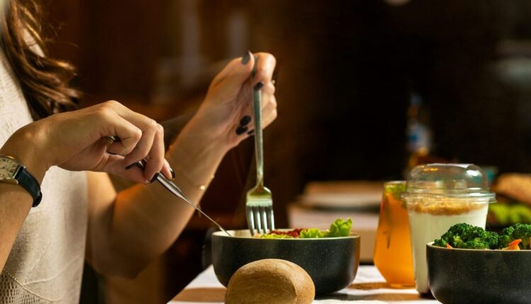 Pessoa fazendo refeição com legumes e pão