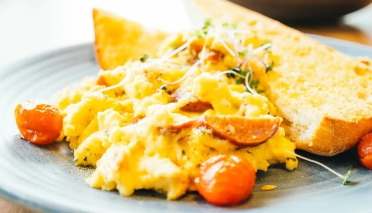 Prato de ovos mexidos cremosos com tomates ao lado