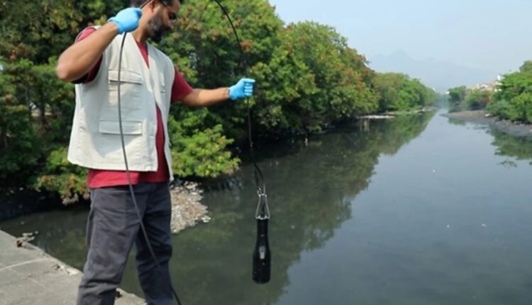 Pesquisador coleta amostra de água em rio urbano