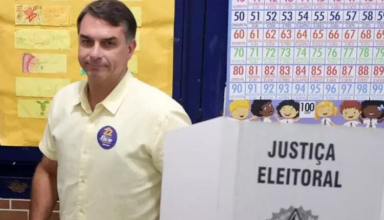 Flávio Bolsonaro ao lado de urna da Justiça Eleitoral