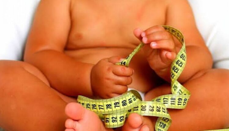 Barriga de criança com fita métrica enrolada na mão