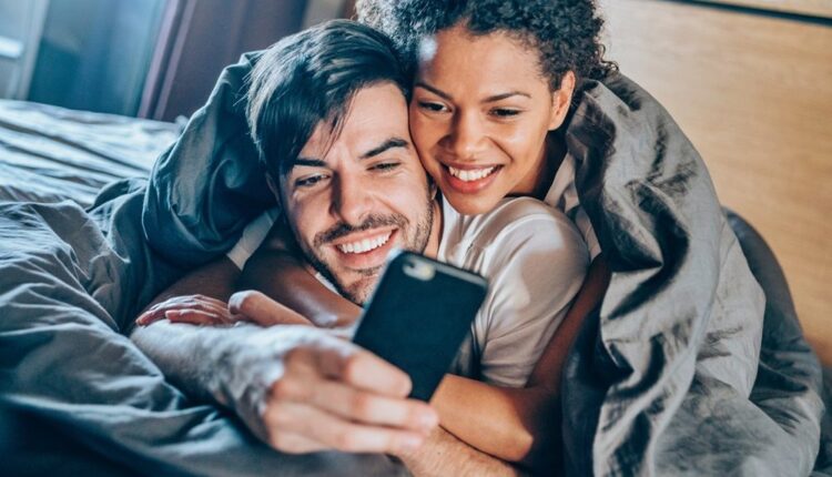 Casal olha o celular junto na cama
