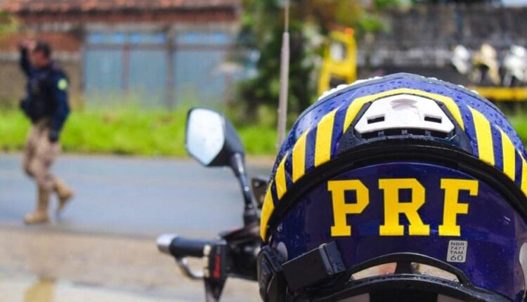 Agente da PRF com capacete ao lado de motocicleta