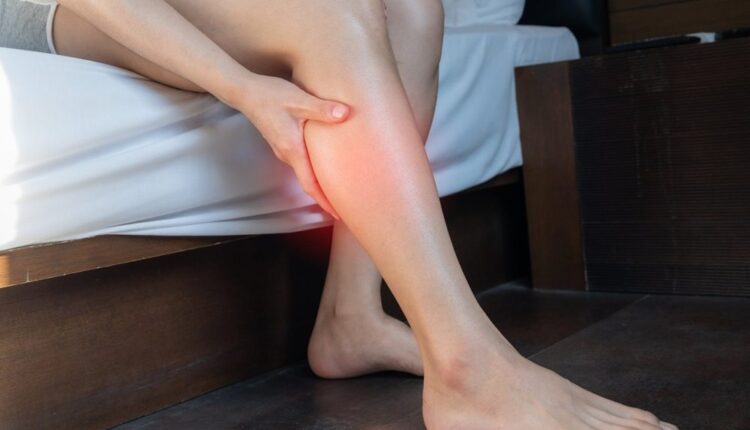 Pessoa sentada na cama com dor nas pernas